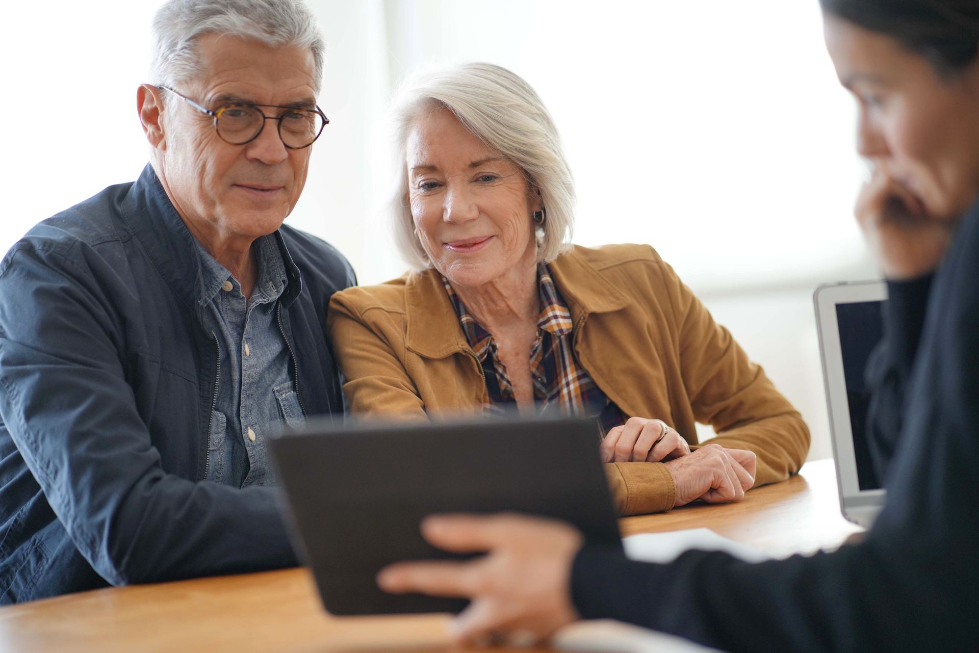 A senior couple reviewing home modification options on a tablet with a consultant