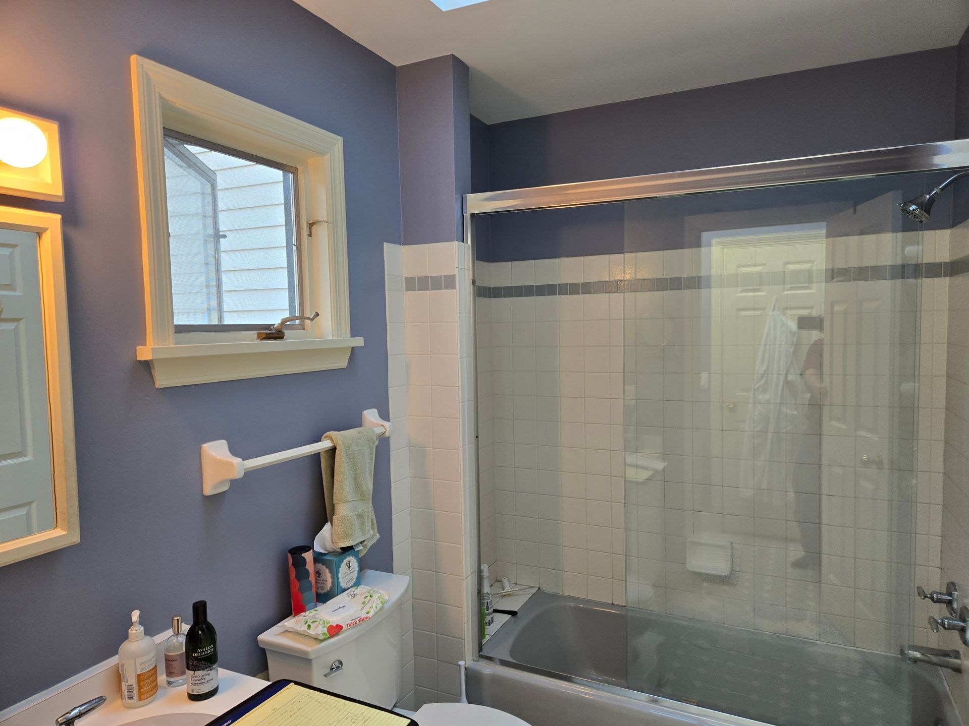 Bathroom with blue walls, vanity sink, mirror, and a glass-enclosed shower.