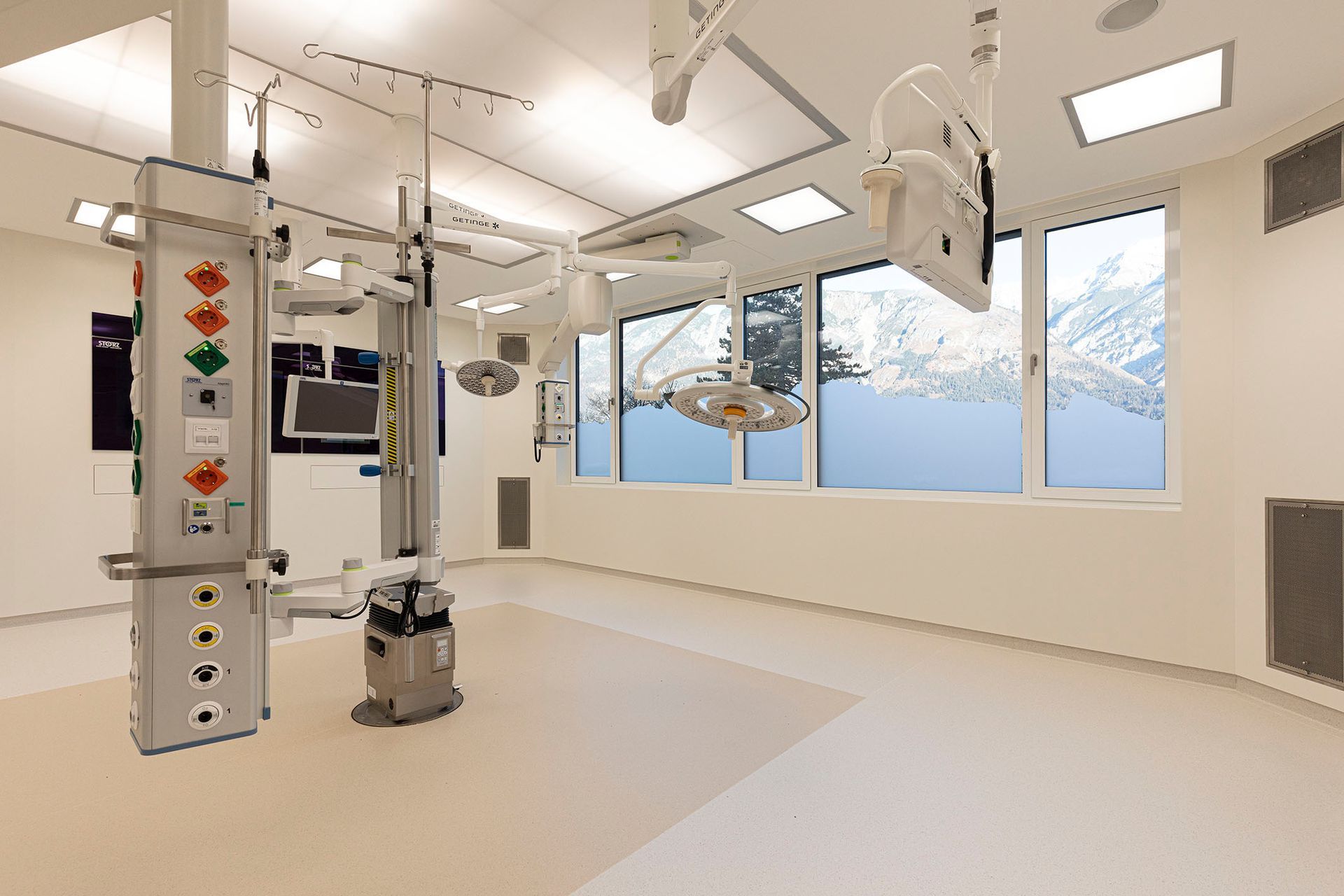 Ein leerer Operationssaal in einem Krankenhaus mit vielen Fenstern und chirurgischen Geräten.