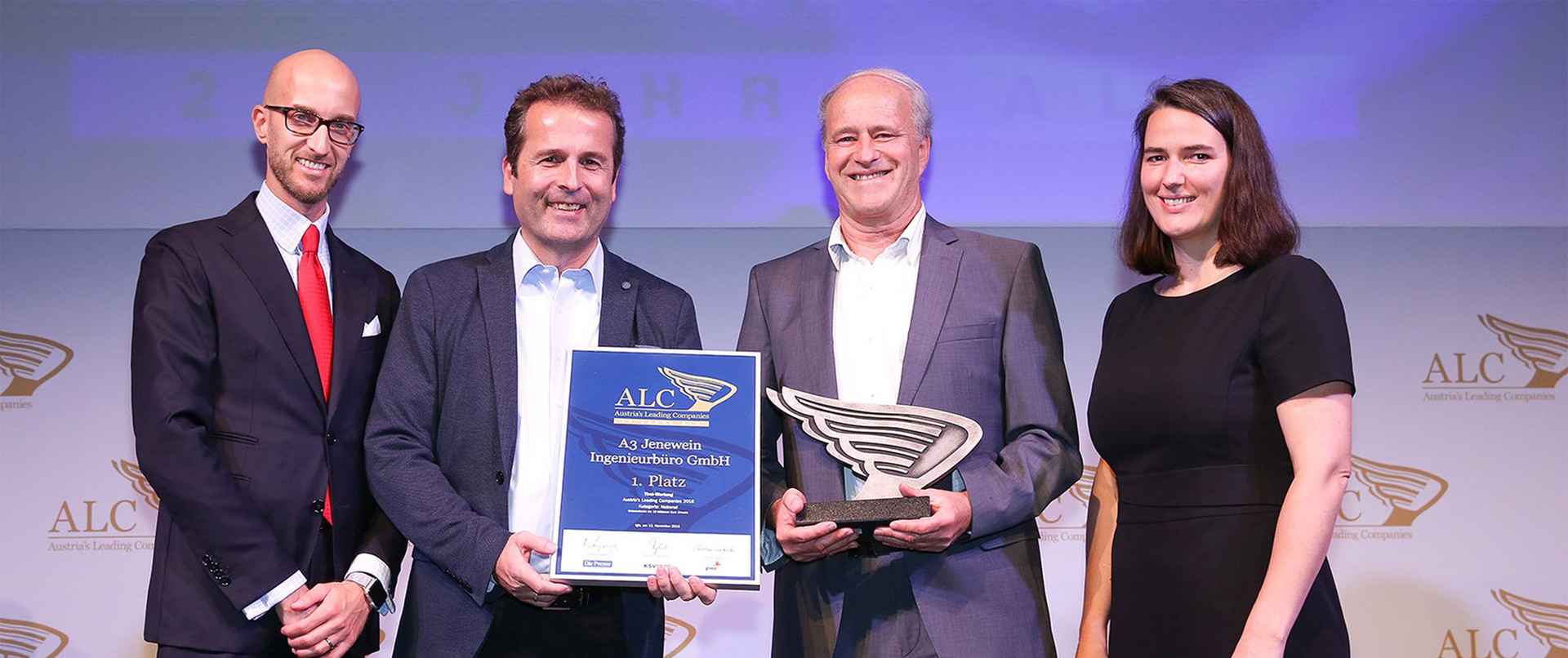 Eine Gruppe von Leuten steht nebeneinander und hält eine Trophäe in den Händen.