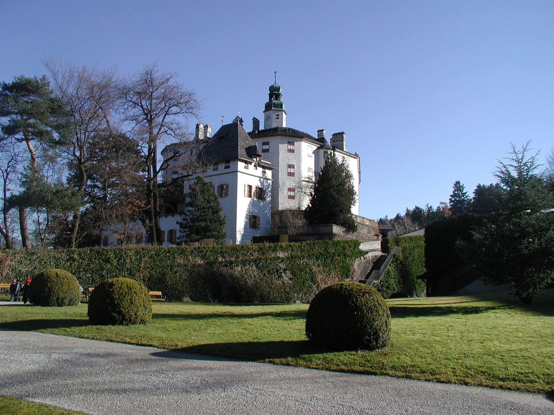 Ein großes weißes Gebäude ist von Bäumen und Büschen umgeben