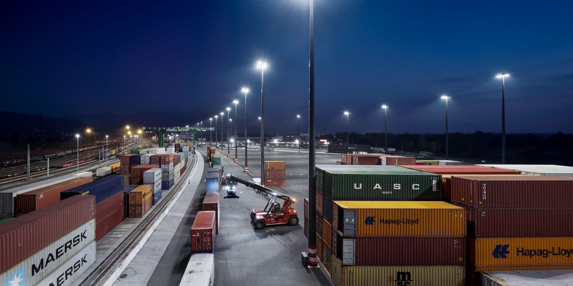 Viele Schiffscontainer stehen nachts in einem Lagerhaus aufgereiht