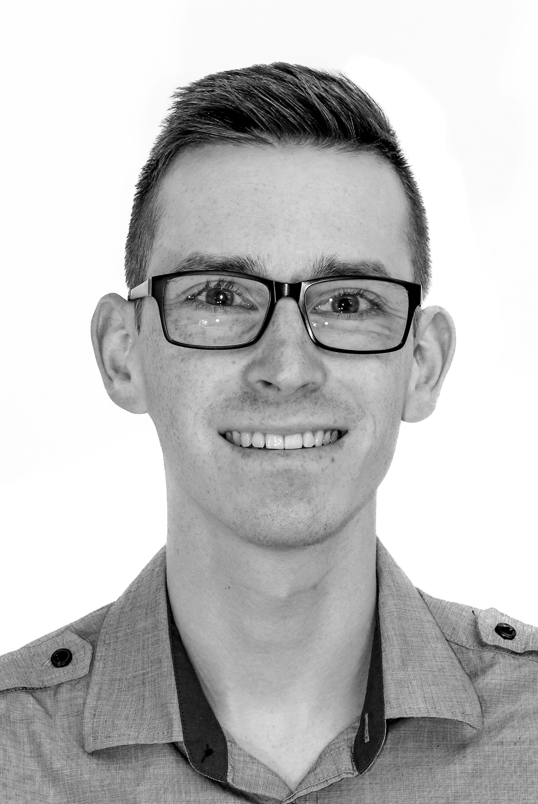 Auf einem Schwarzweißfoto lächelt ein Mann mit Brille.