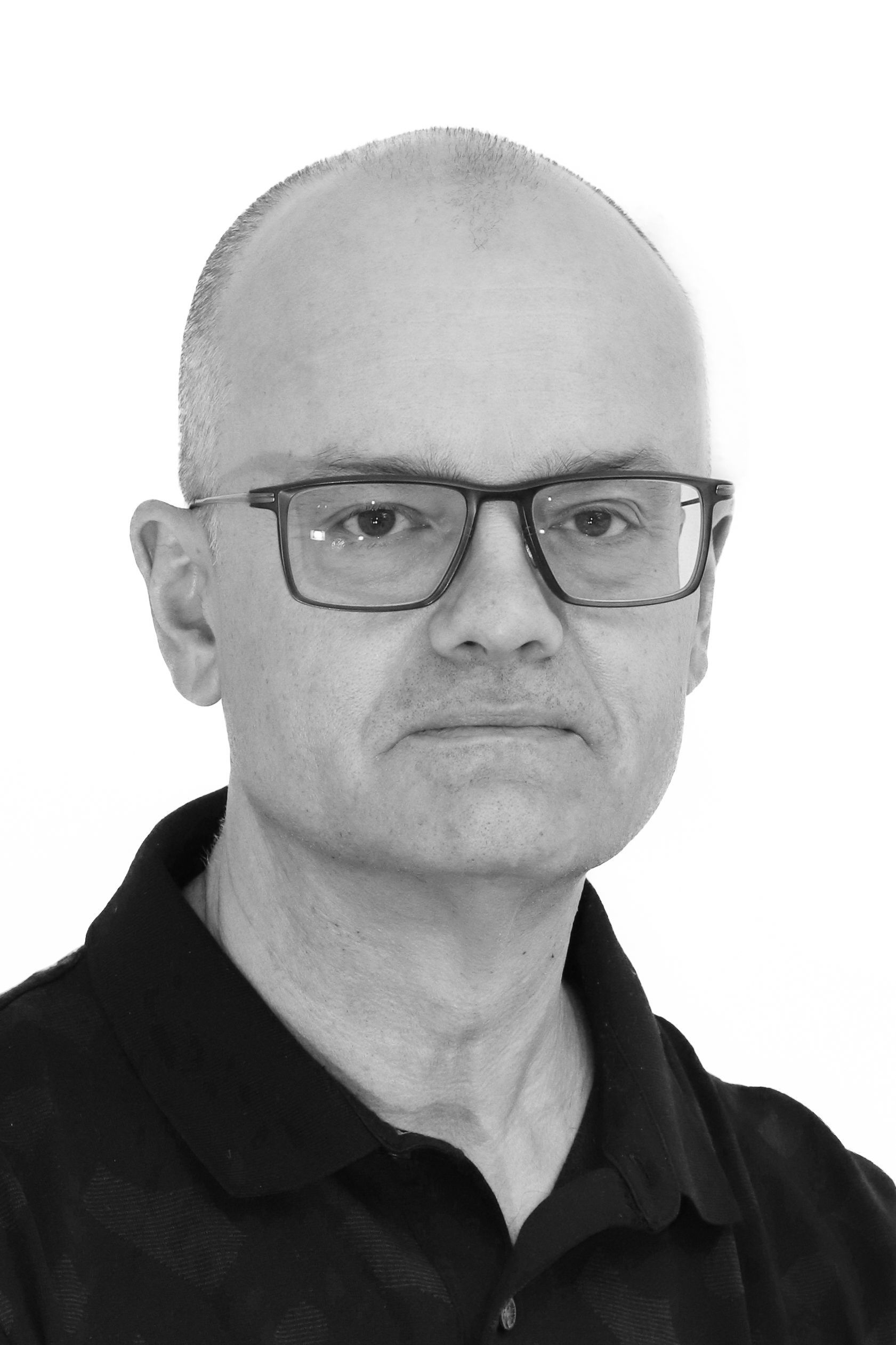 Ein Mann mit Brille und schwarzem Hemd schaut in die Kamera.