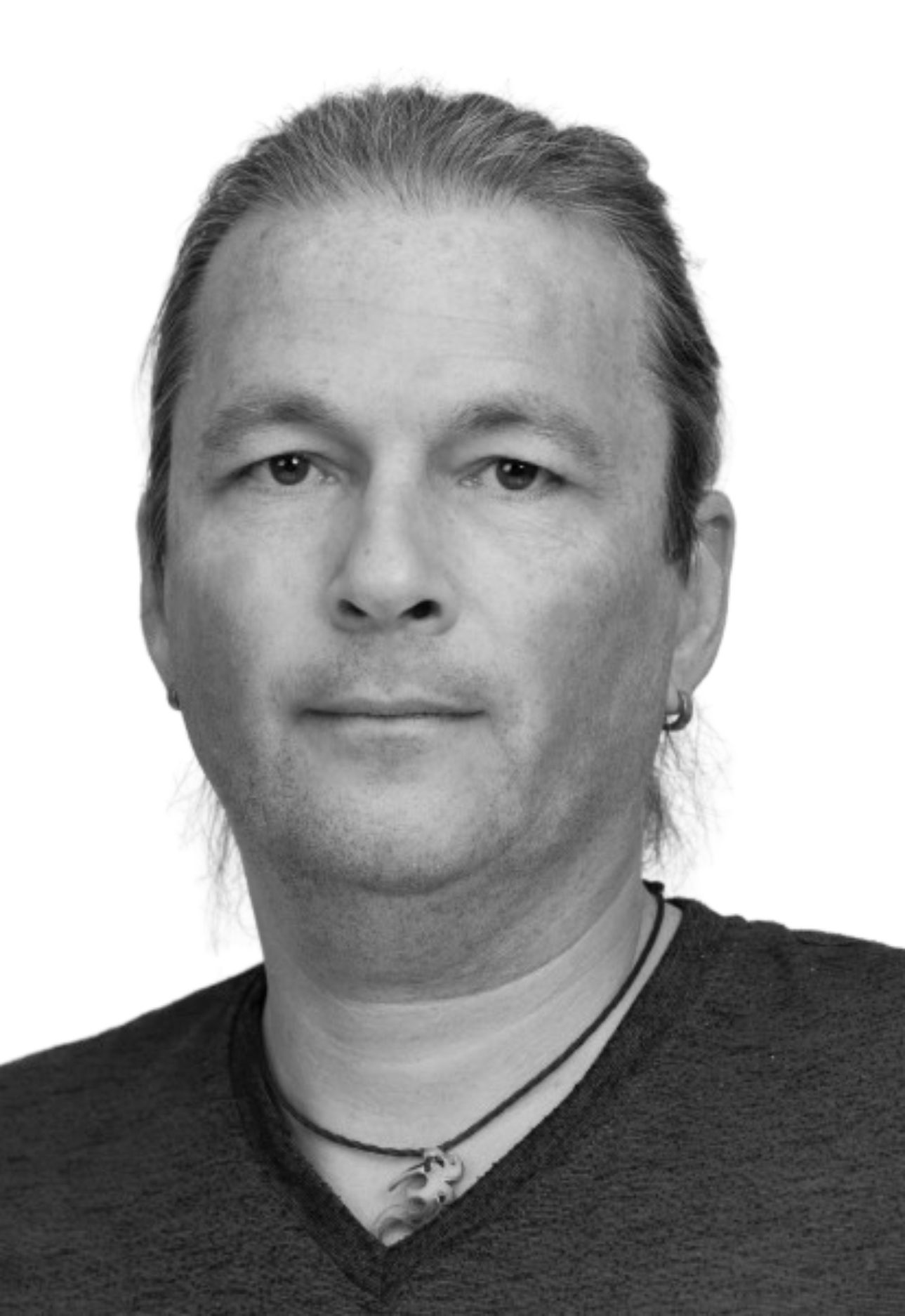 Ein Mann mit langen Haaren und Brille trägt eine Halskette.