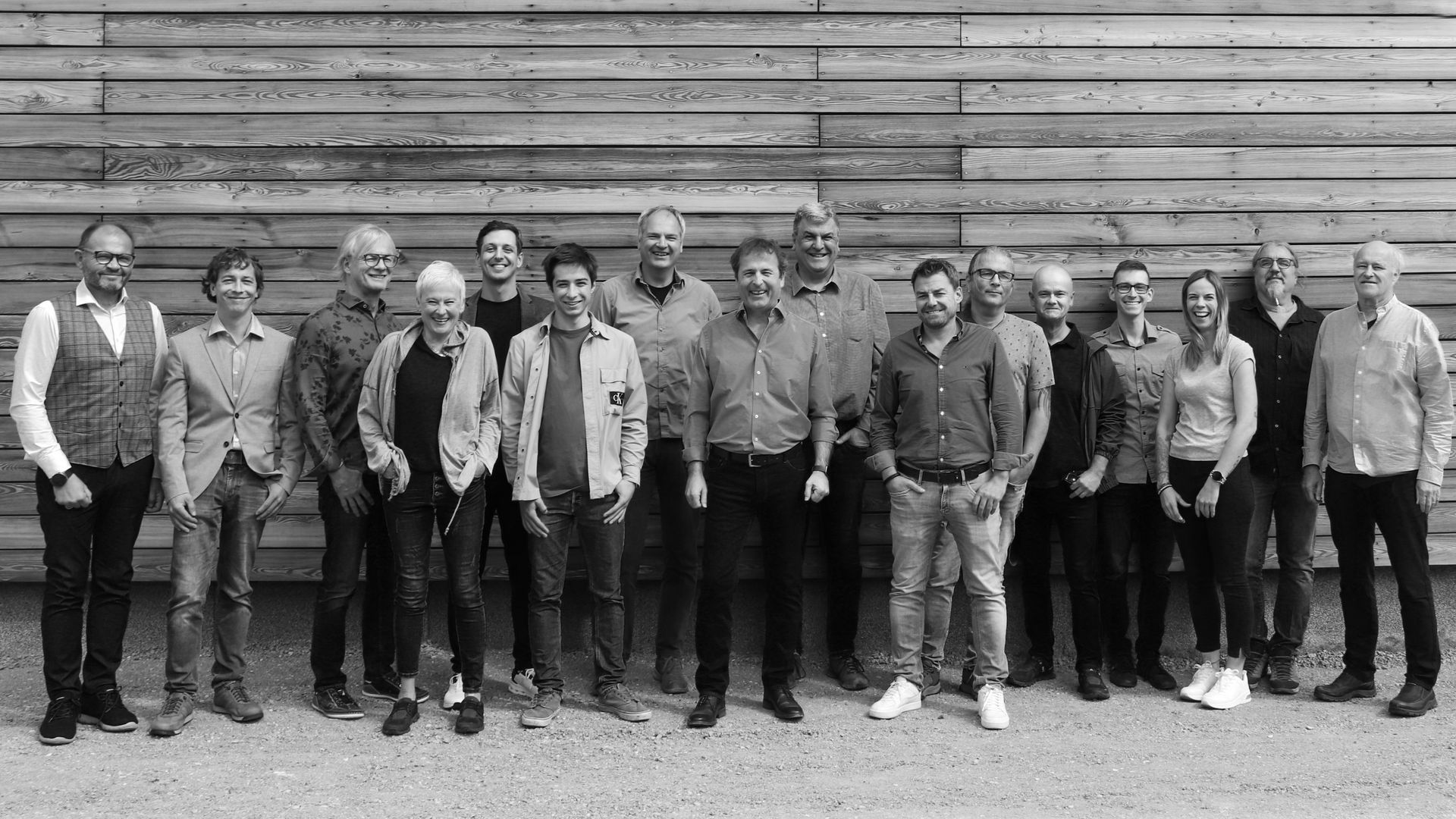 Ein Schwarzweißfoto einer Gruppe von Menschen, die vor einer Holzwand stehen.