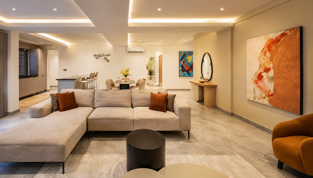 Furnished Apartments in Addis Ababa feature a lounge with sectional sofa, warm lighting, artwork and stone floors space.