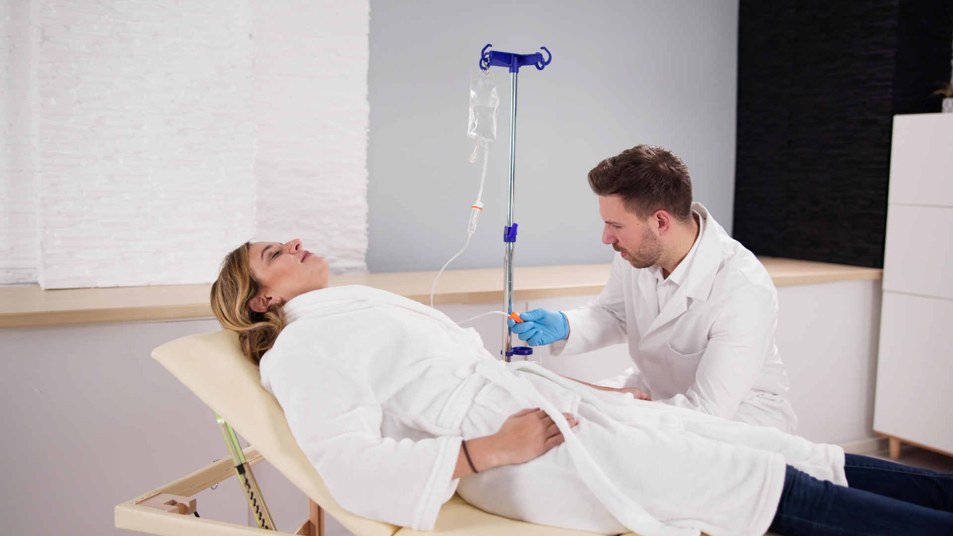 Person receiving IV fluids from a doctor in a medical setting.
