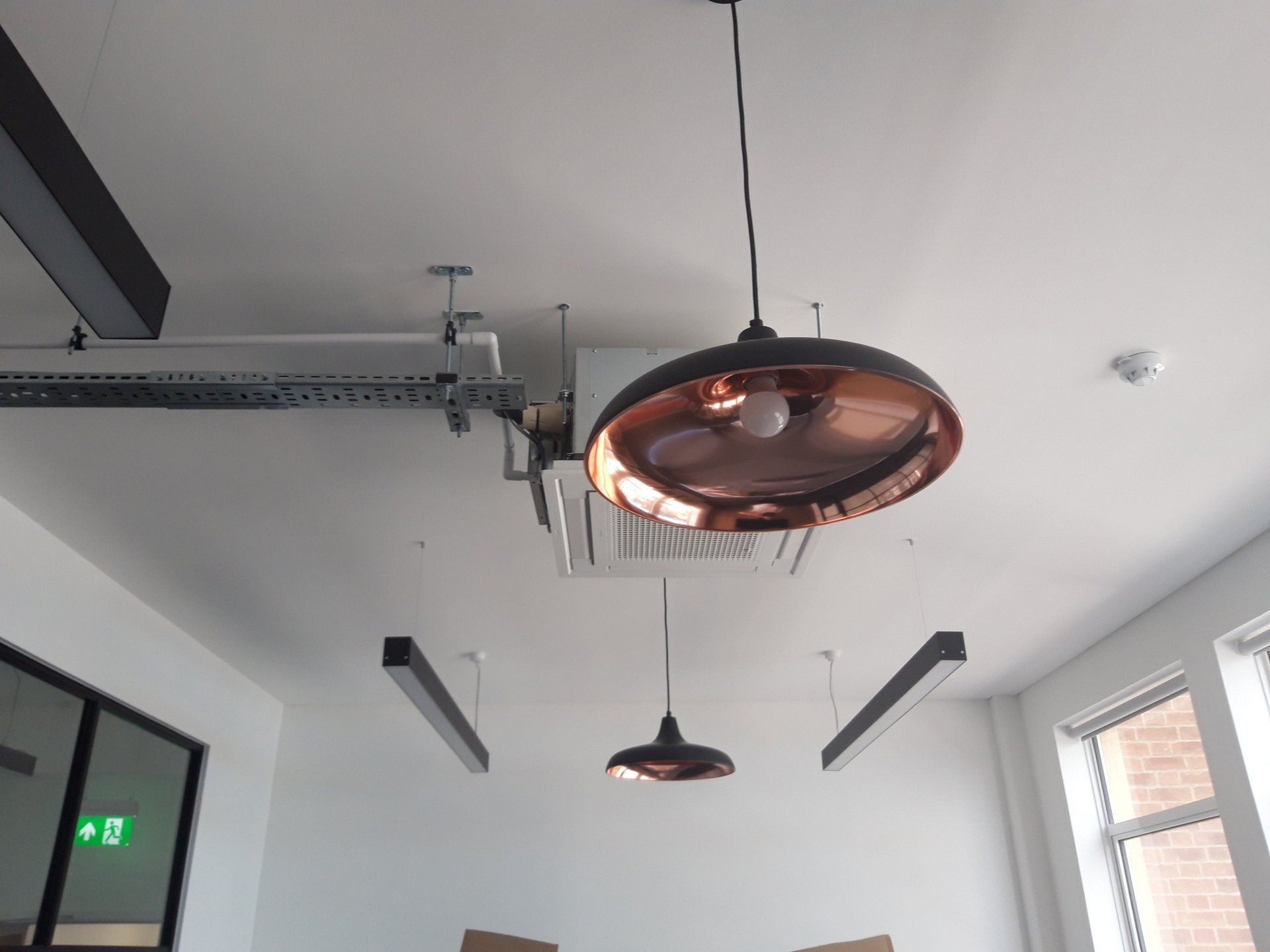 Ceiling view of a modern room with hanging industrial lights and exposed rails.
