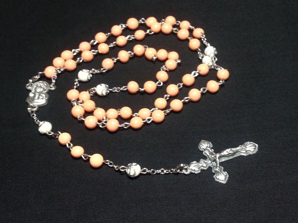 a rosary with orange beads and a silver cross