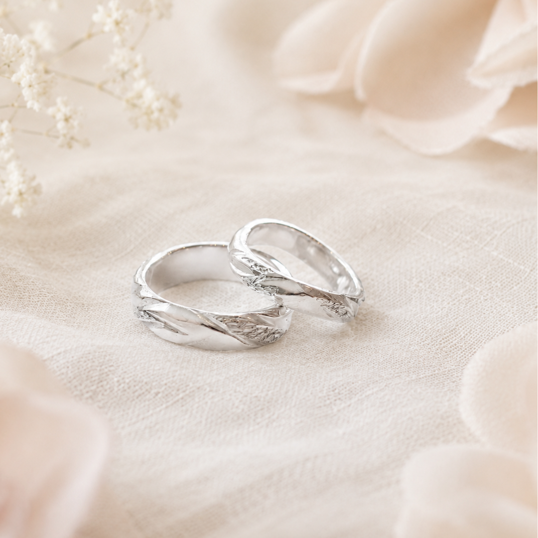 Twee witgouden ringen op een zachte witte stof met delicate bloemen eromheen.
