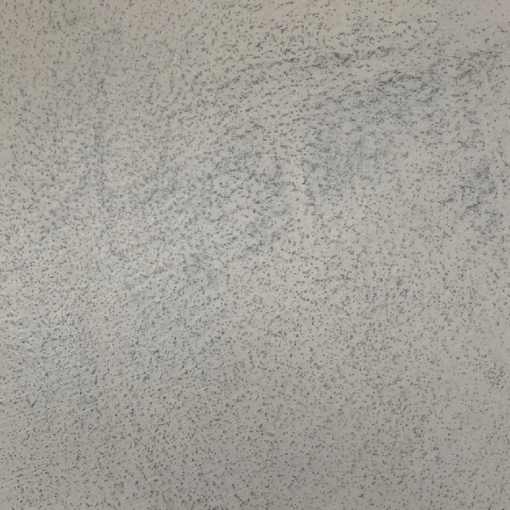 Close-up of a light gray textured surface with scattered dark speckles