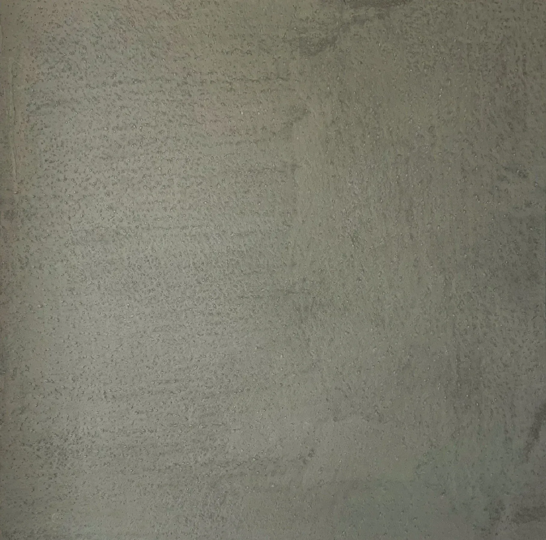 Close-up of a gray textured wall with subtle stains and shadows