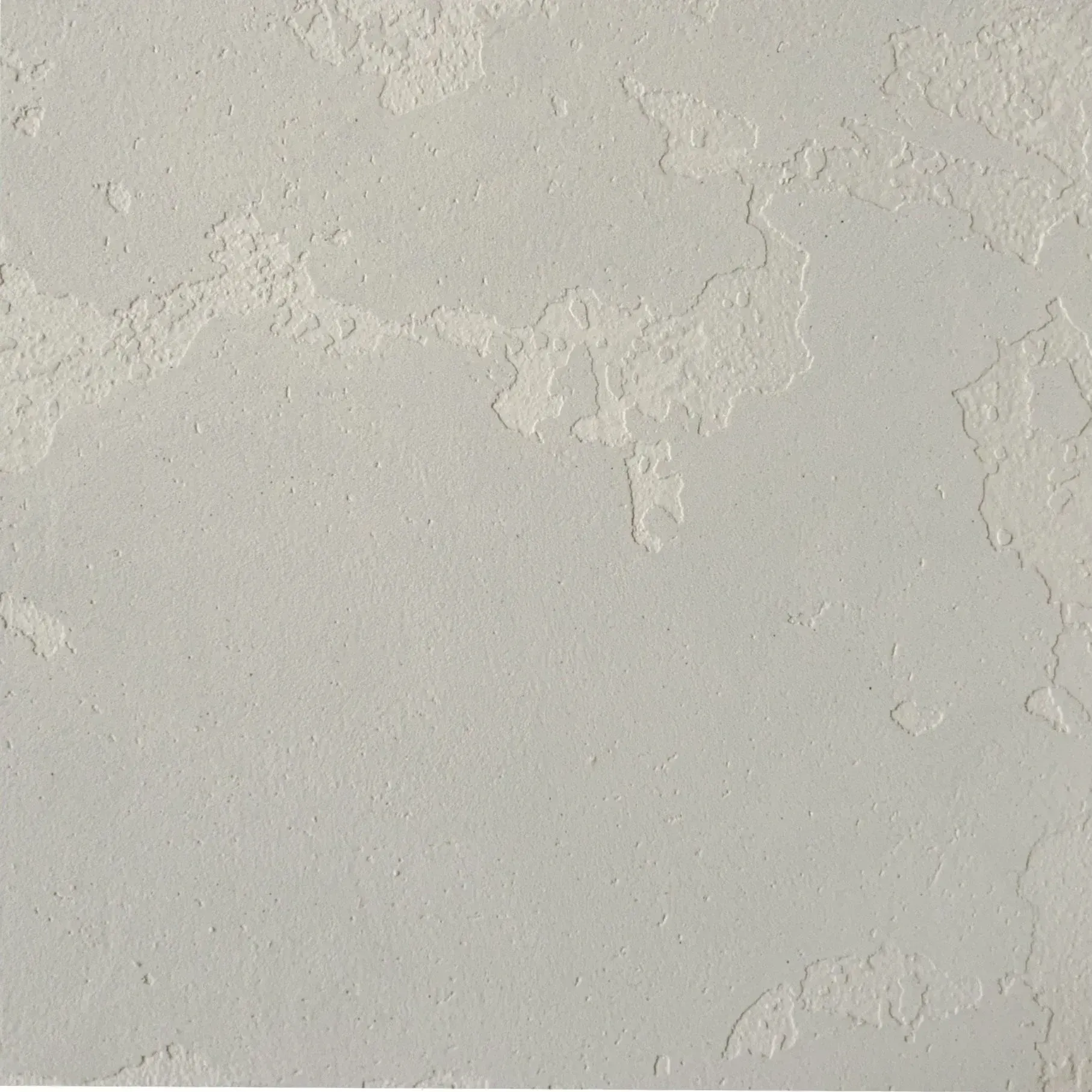 Close-up of a light gray textured wall with subtle plaster patches