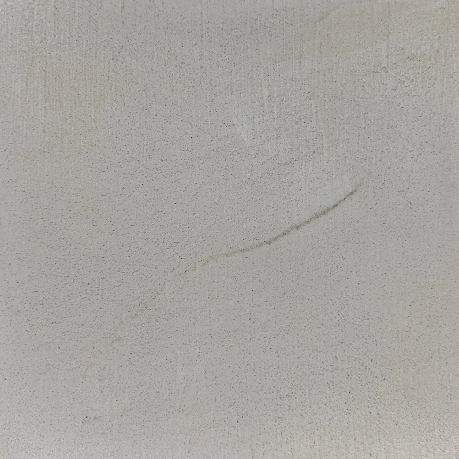 Beige textured wall with a faint, thin, diagonal dark streak.