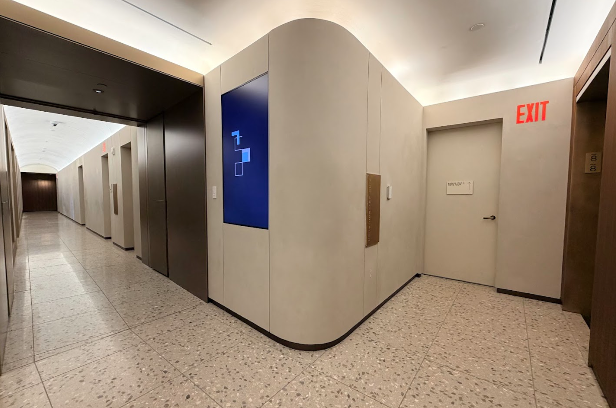 Modern hallway with curved wall, blue sign, and exit door in a bright building lobby