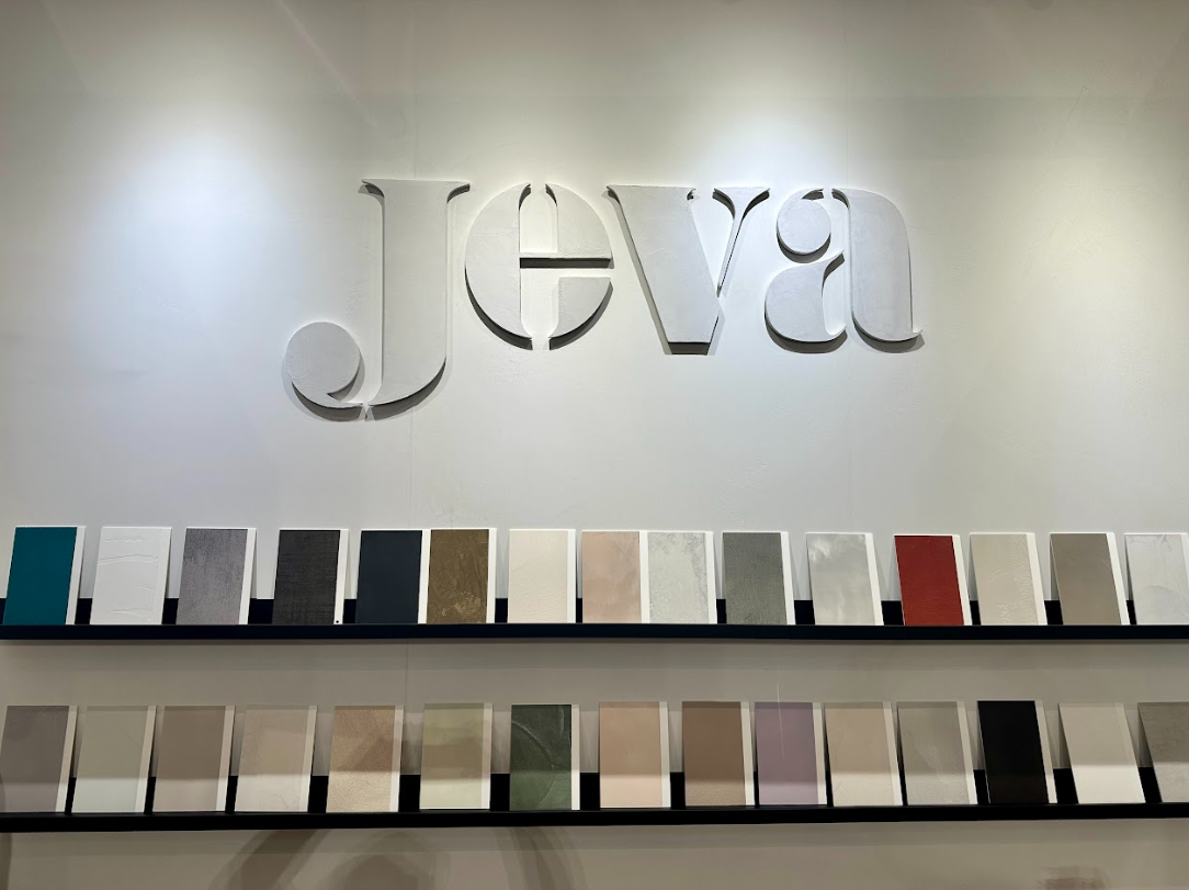 Jeva logo on a wall above shelves of fabric swatches in a showroom