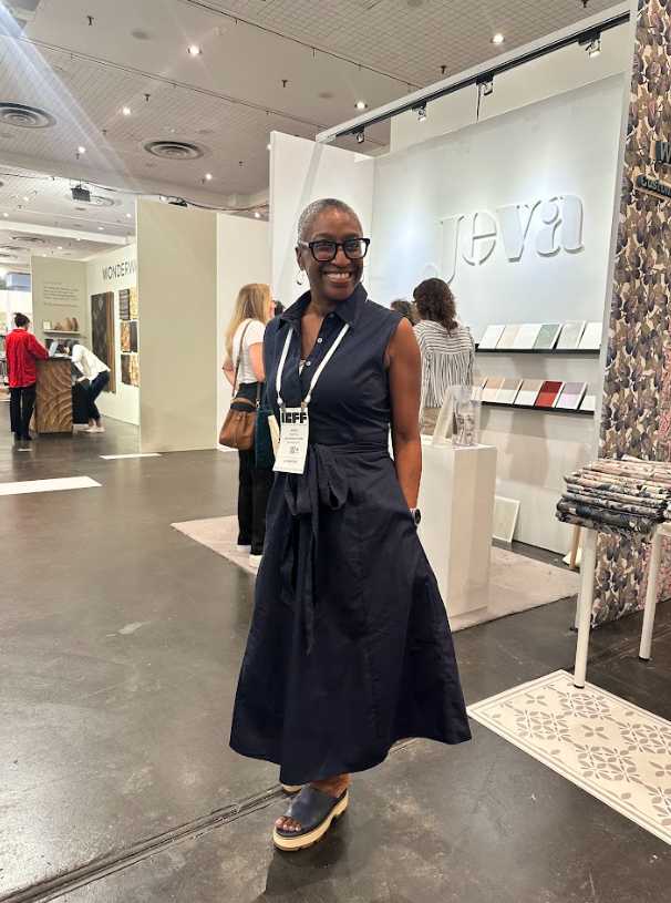 Smiling woman in a dark dress posing in a retail store with jewelry displays and shelves in the background