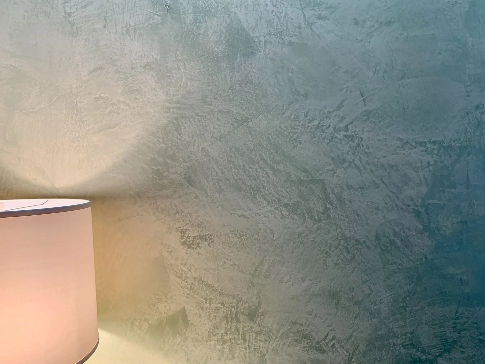 Lamp next to a wall with a textured blue-green finish.