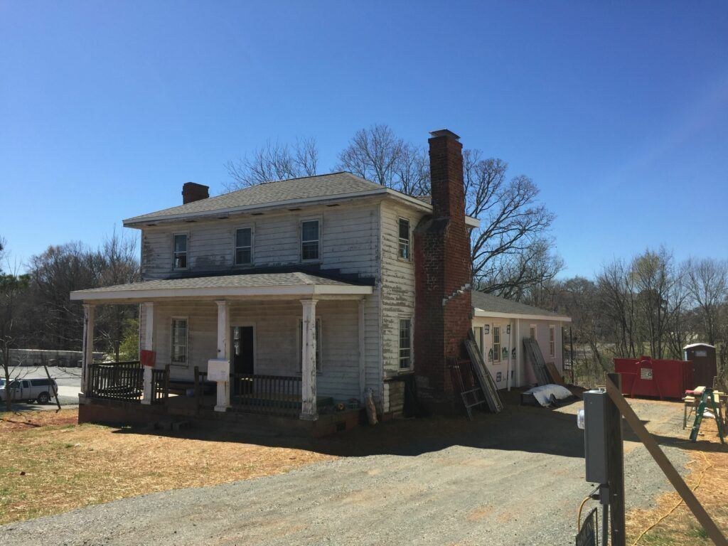 A large white house with a large porch and a chimney.