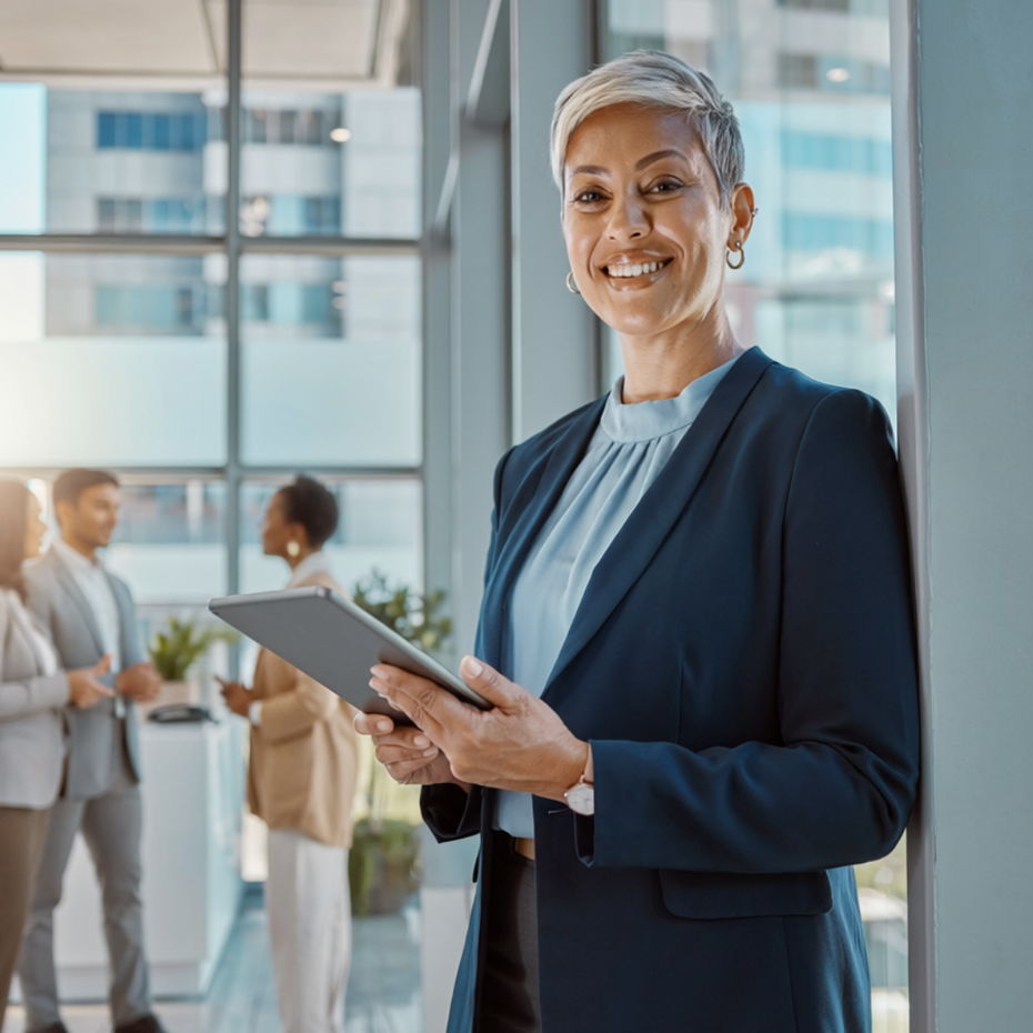 Business professional holding a tablet in a bright office lobby, smiling at the camera