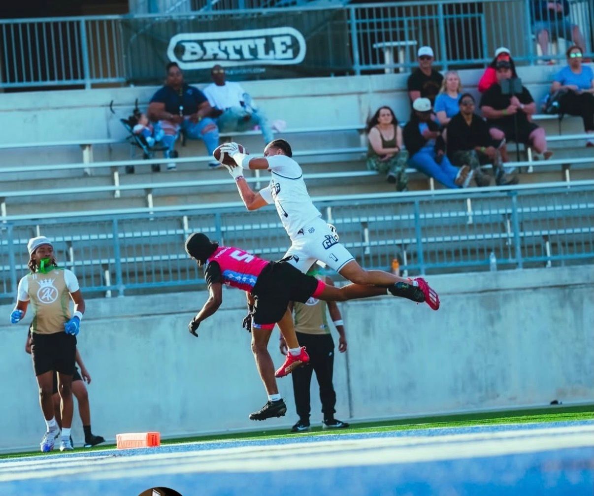 Football players jumping for a catch near the end zone with spectators seated in the stands