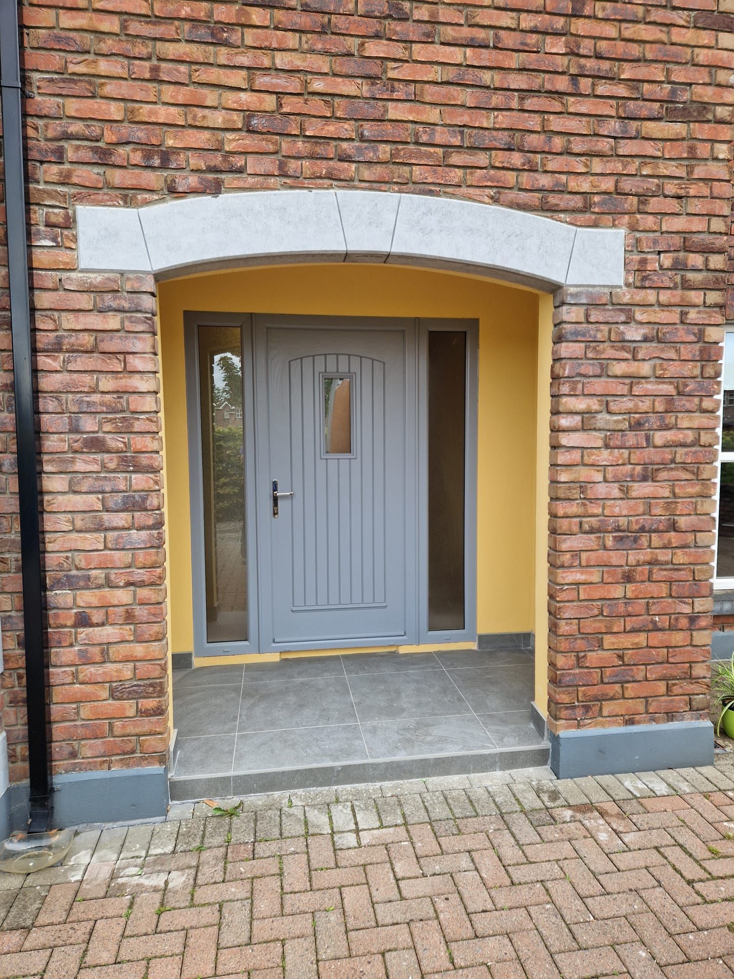 A brick building with a gray door and a yellow wall.