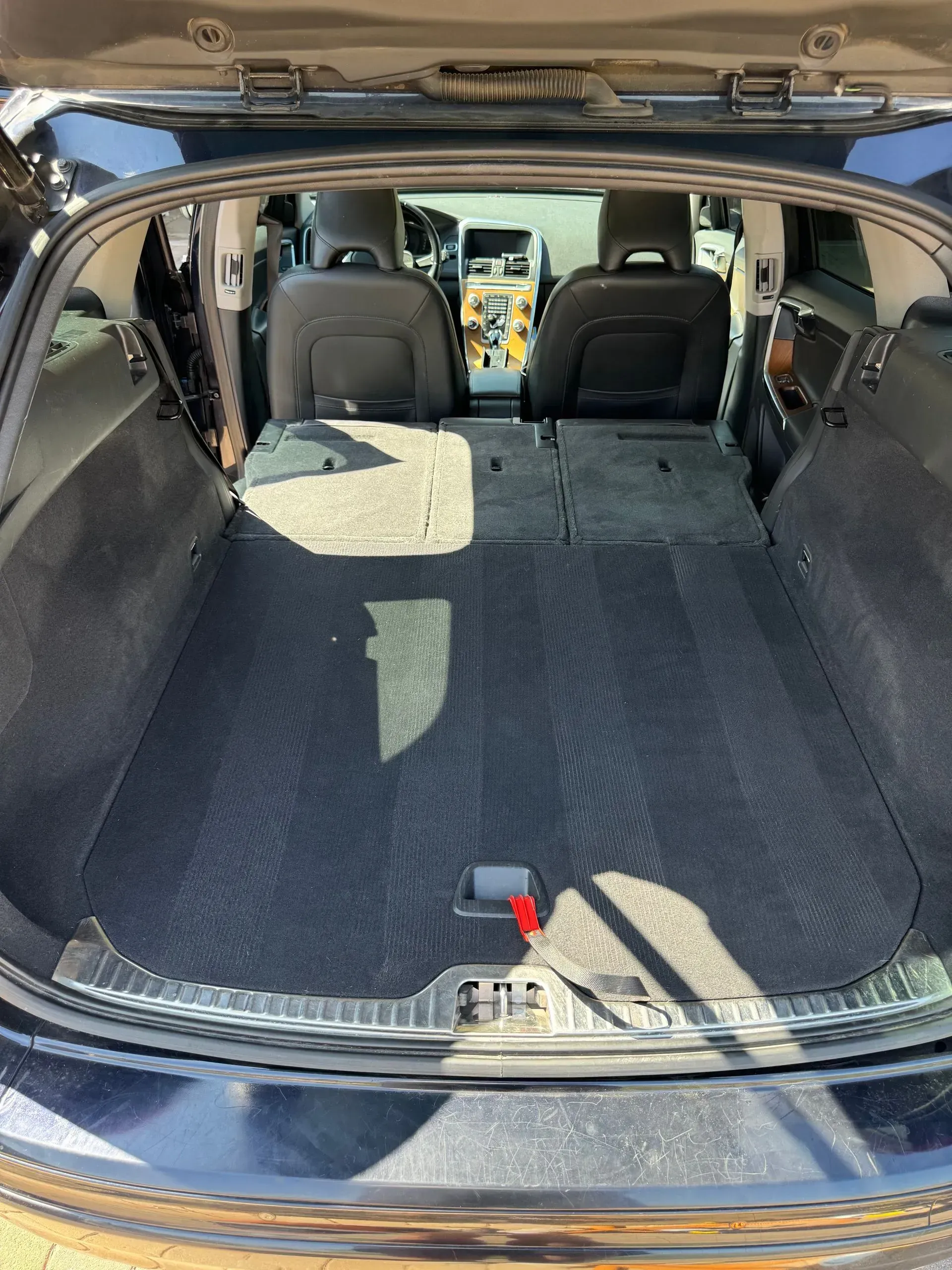 Open black car trunk with folded-down back seats, revealing a flat, dark cargo area.