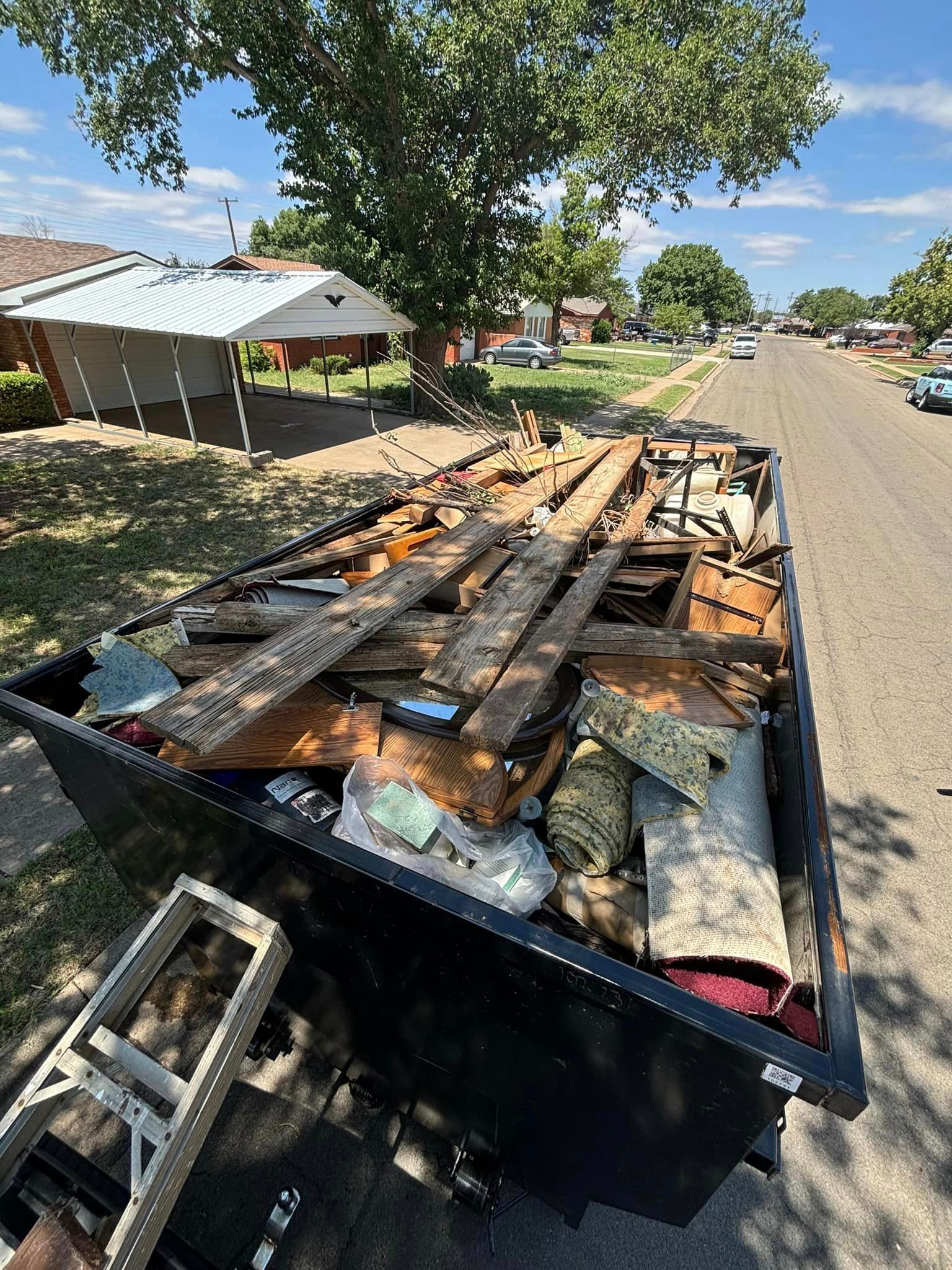 A dumpster filled with junk is parked on the side of the road.