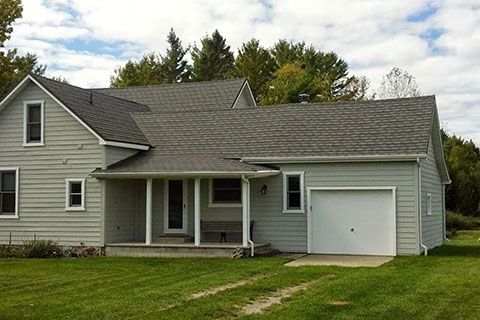 A house with a gray roof and a white garage door
