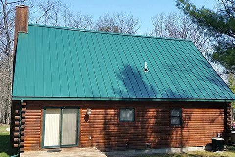 A log cabin with a green metal roof