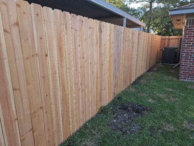 A wooden fence is in the backyard of a house.