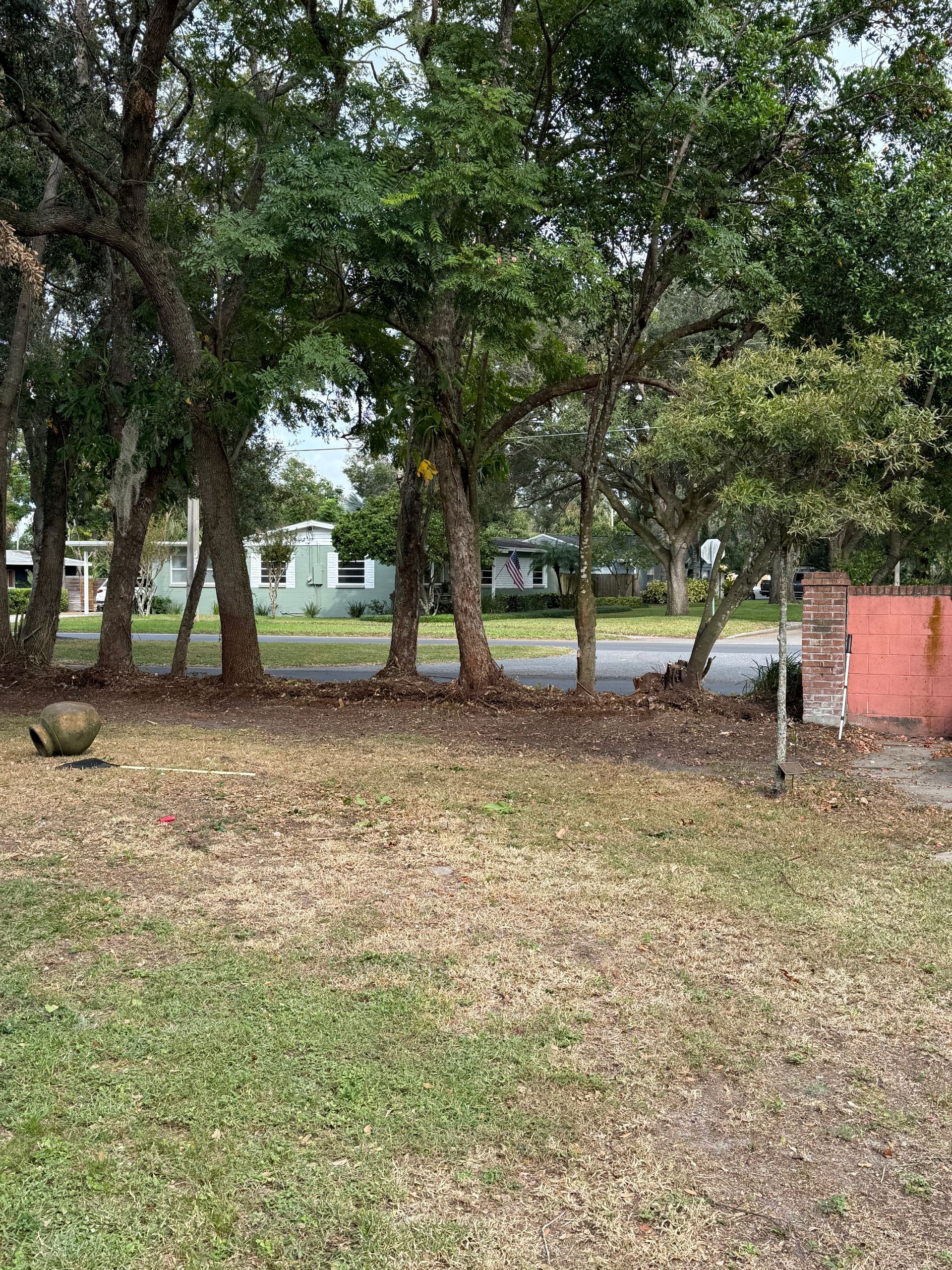 A lawn with trees and a red building in the background.