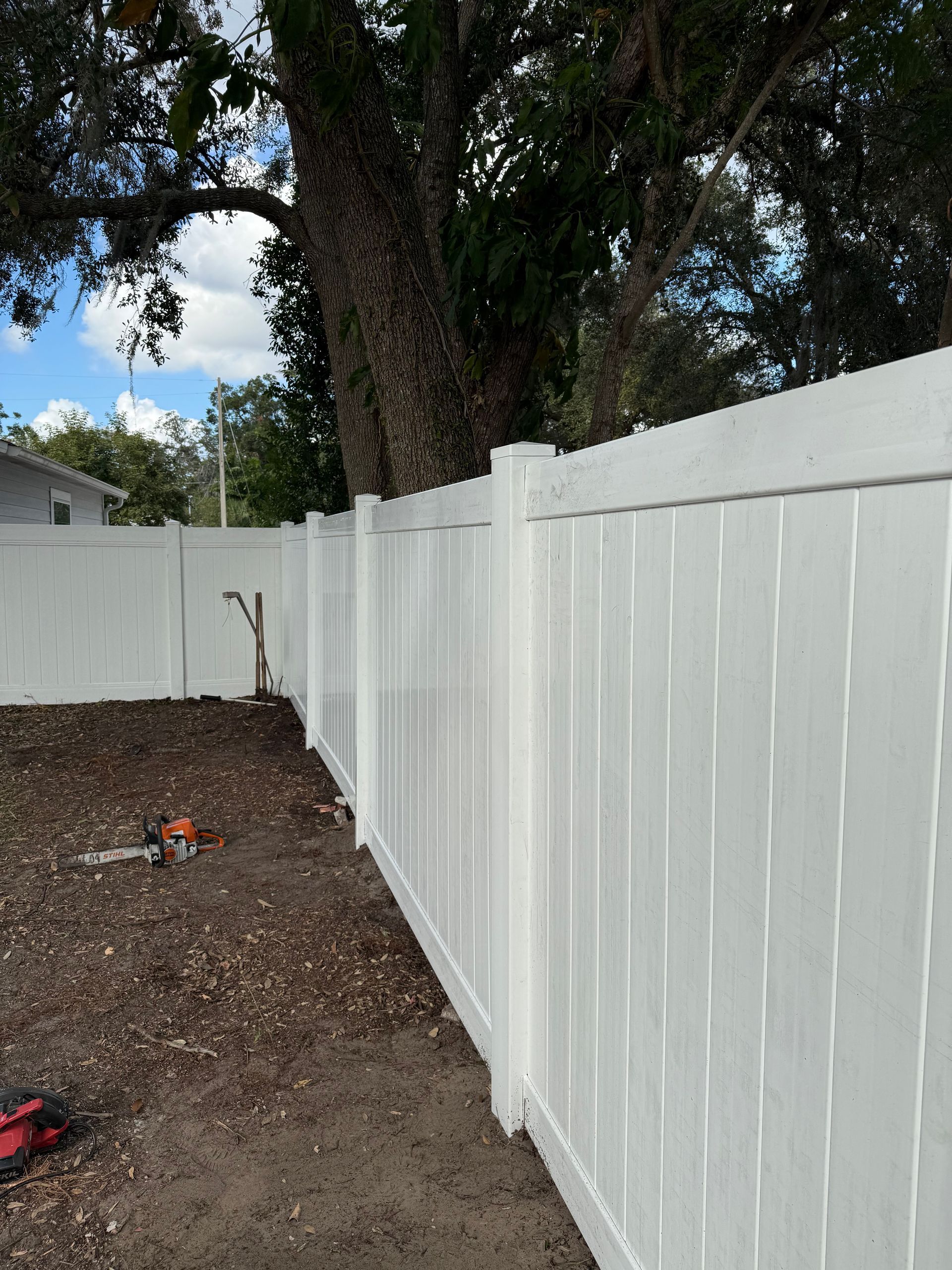 A white fence is being built in a backyard.