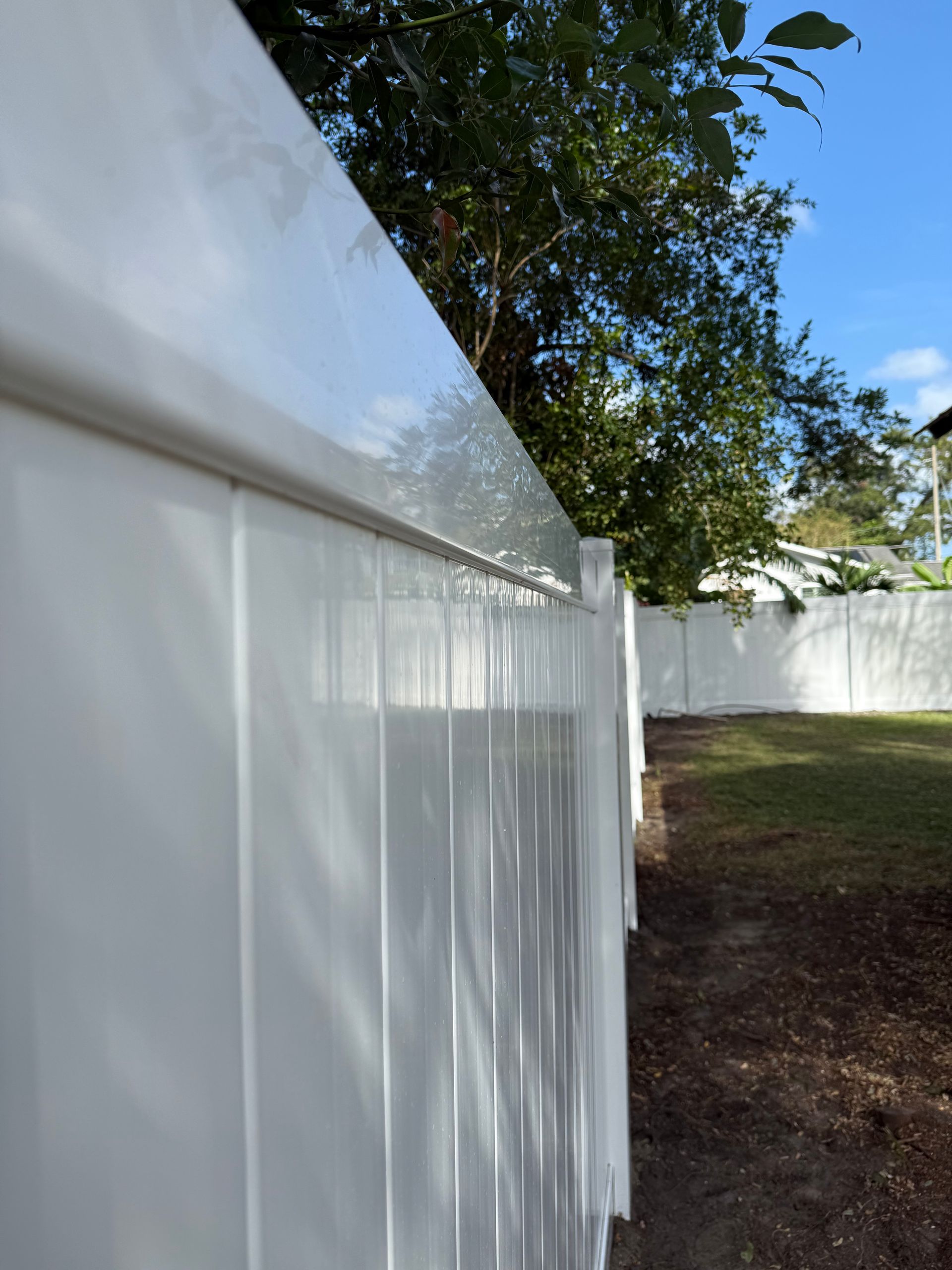 A close up of a white fence with trees in the background