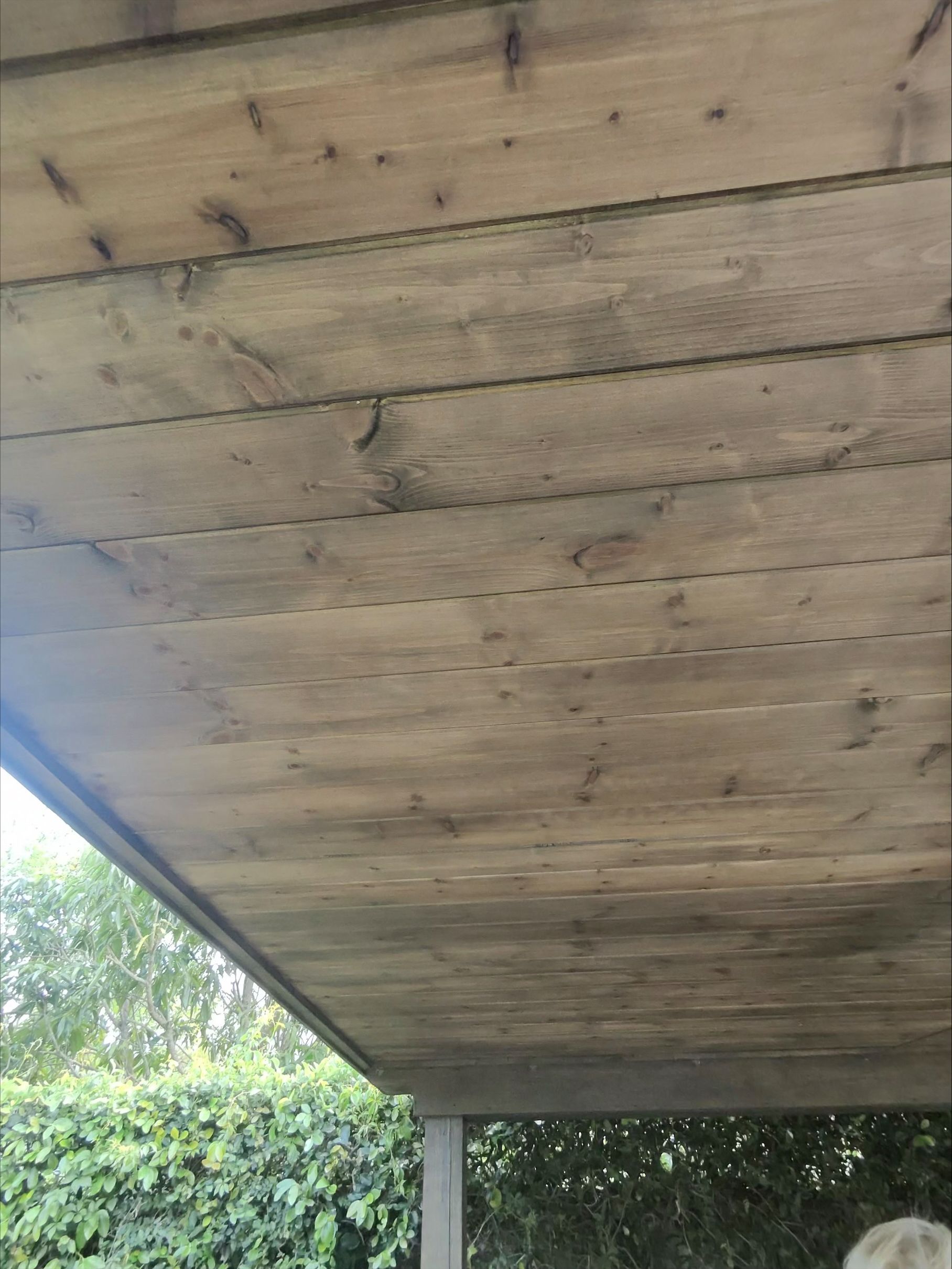 A person is standing under a wooden roof.