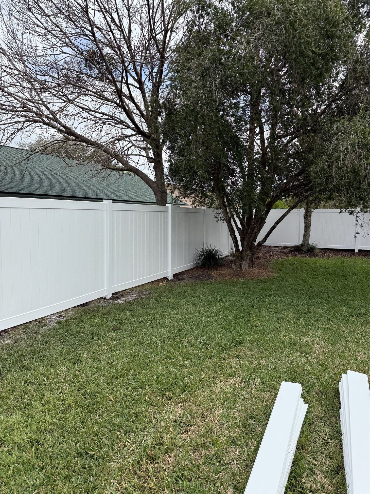 A white vinyl fence surrounds a lush green yard.