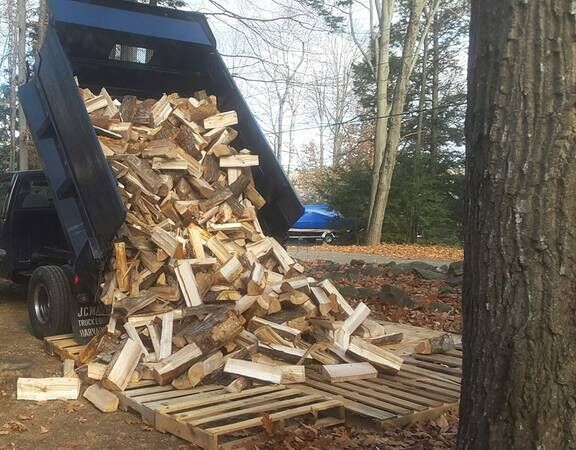 A pile of wood is being loaded into a dumpster.