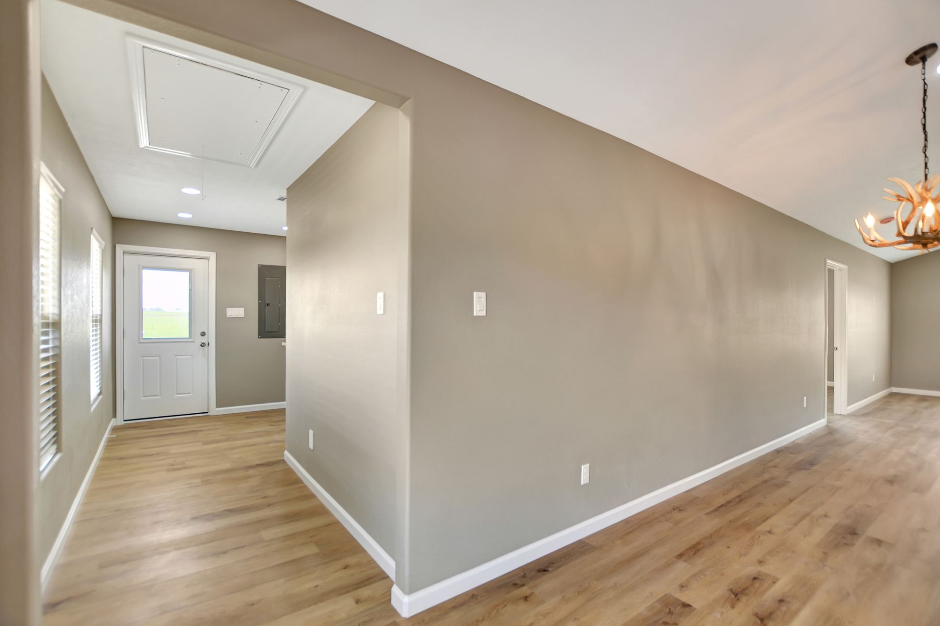 Interior view of a home with light wood floors, gray walls, and a view of a door.
