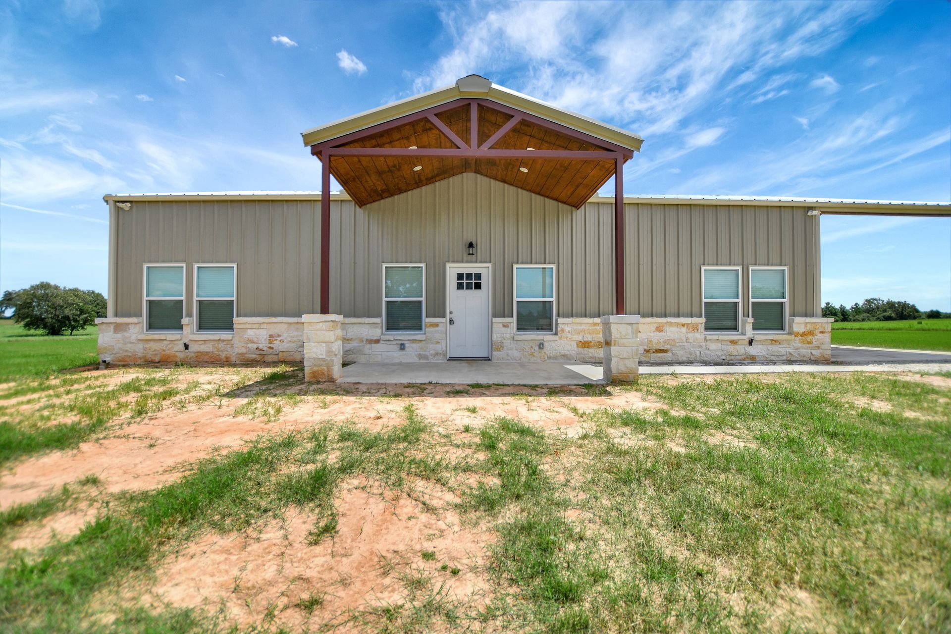 Tan metal-clad ranch home with a covered porch on a sunny day.