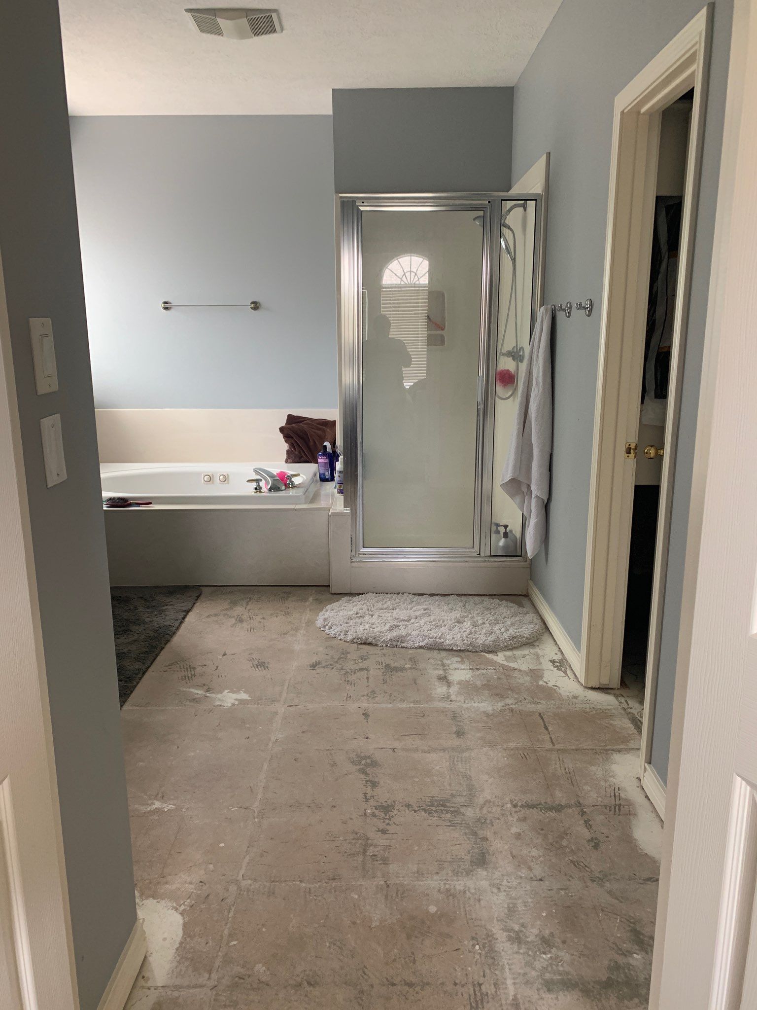 Bathroom with a tub, shower, and dirty floor with a doorway on the right.