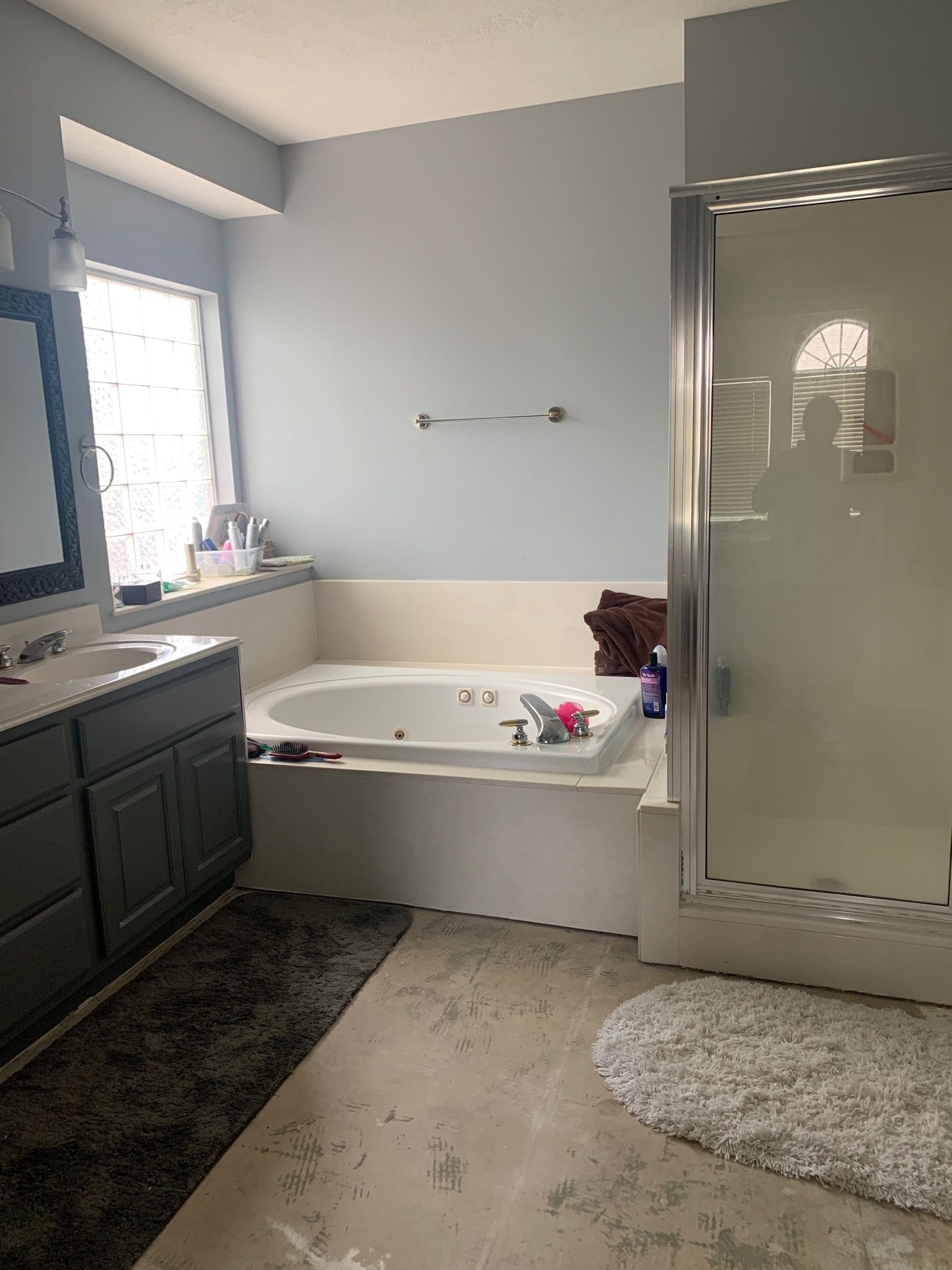 Bathroom with tub, shower, vanity. Gray walls, white tub, dark gray vanity, gray rug.