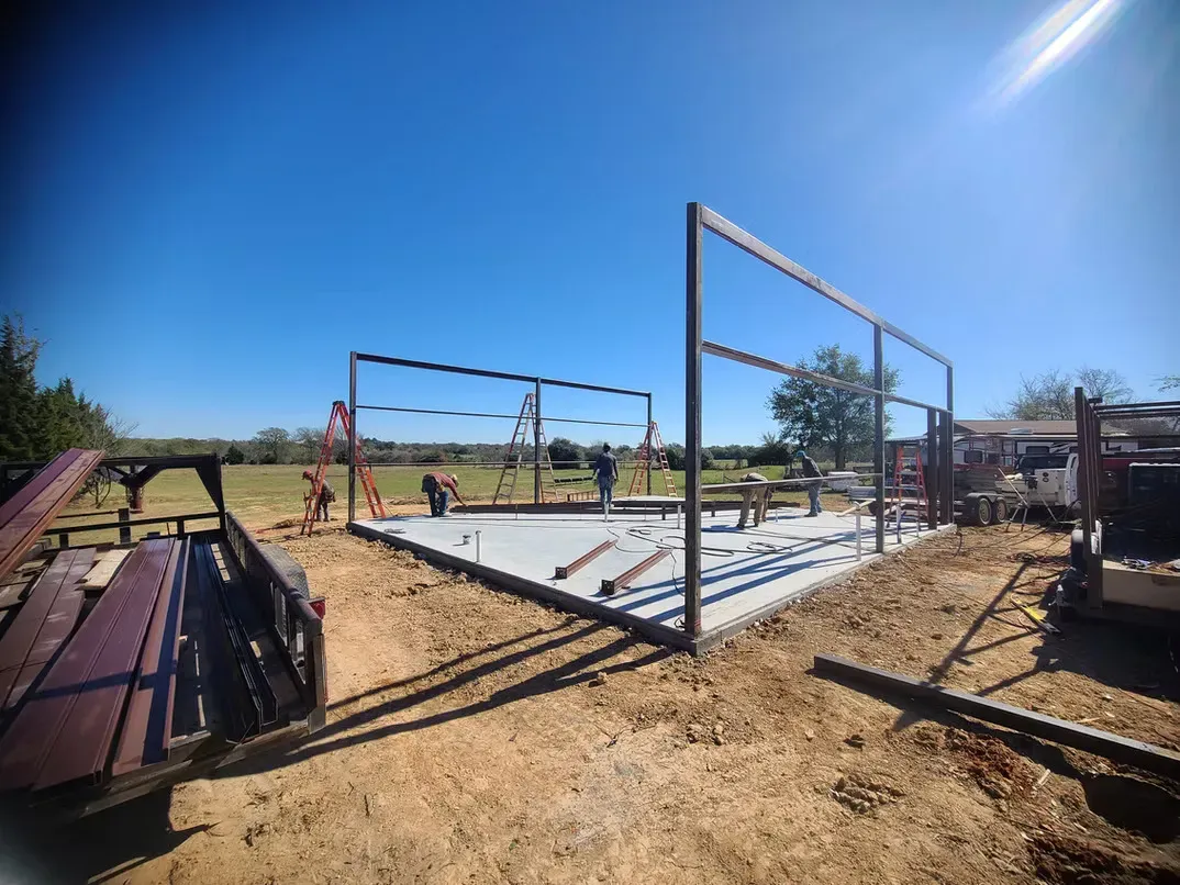 A large metal structure is being built in a dirt field.