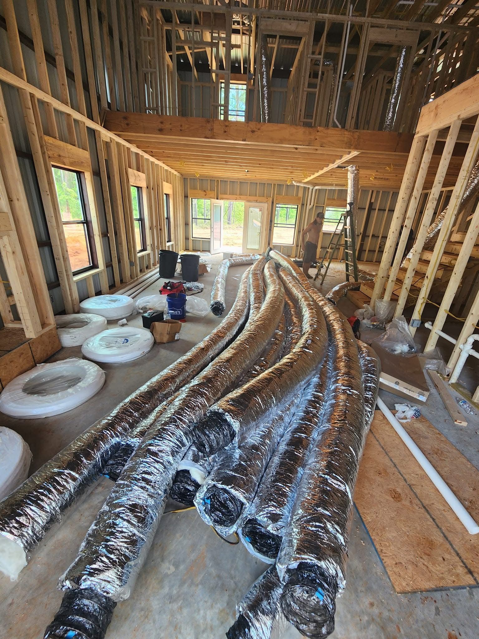 Interior of a house under construction with flexible ductwork and exposed wooden framing.