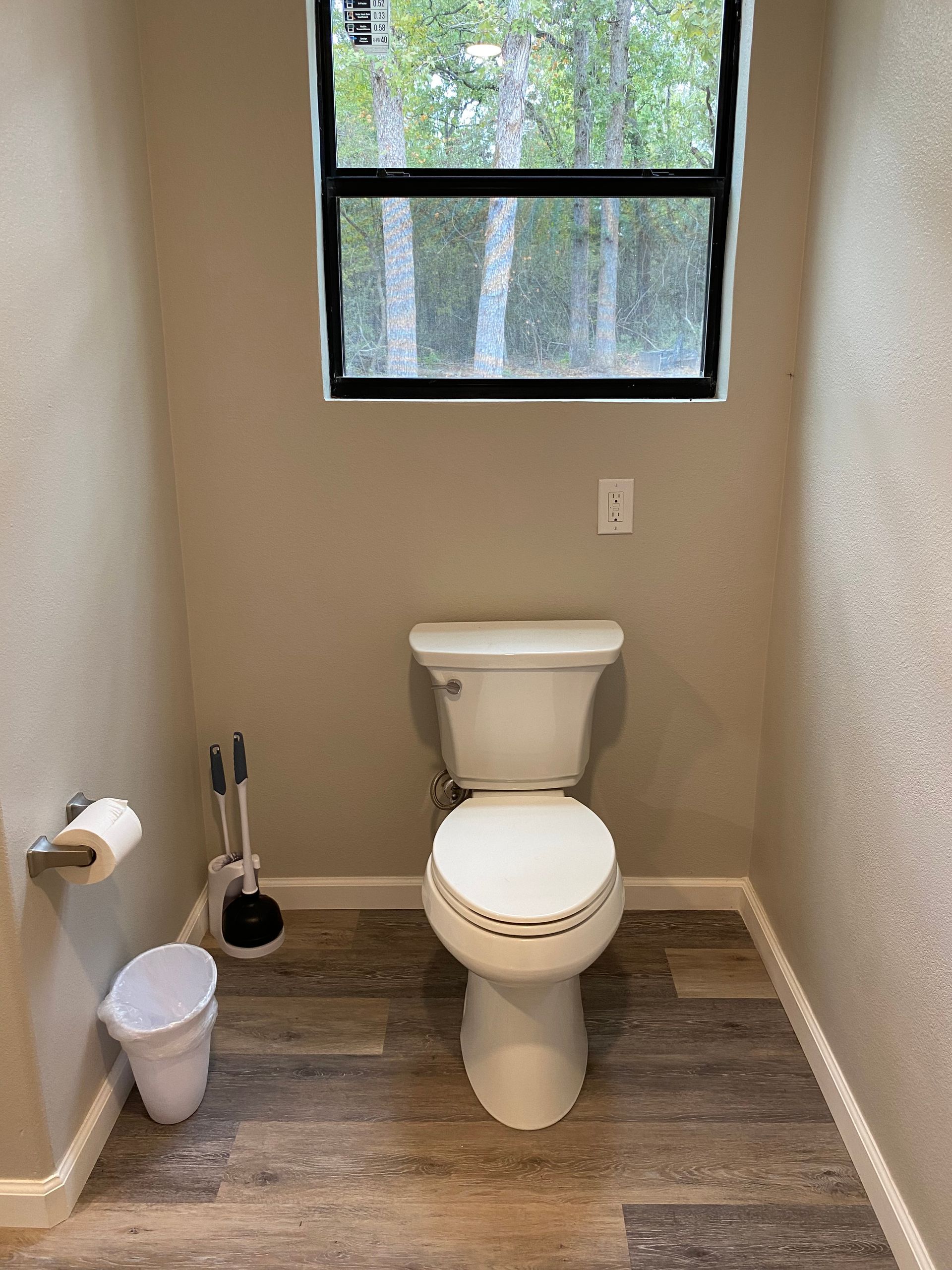 Small bathroom with a toilet, window, and accessories.