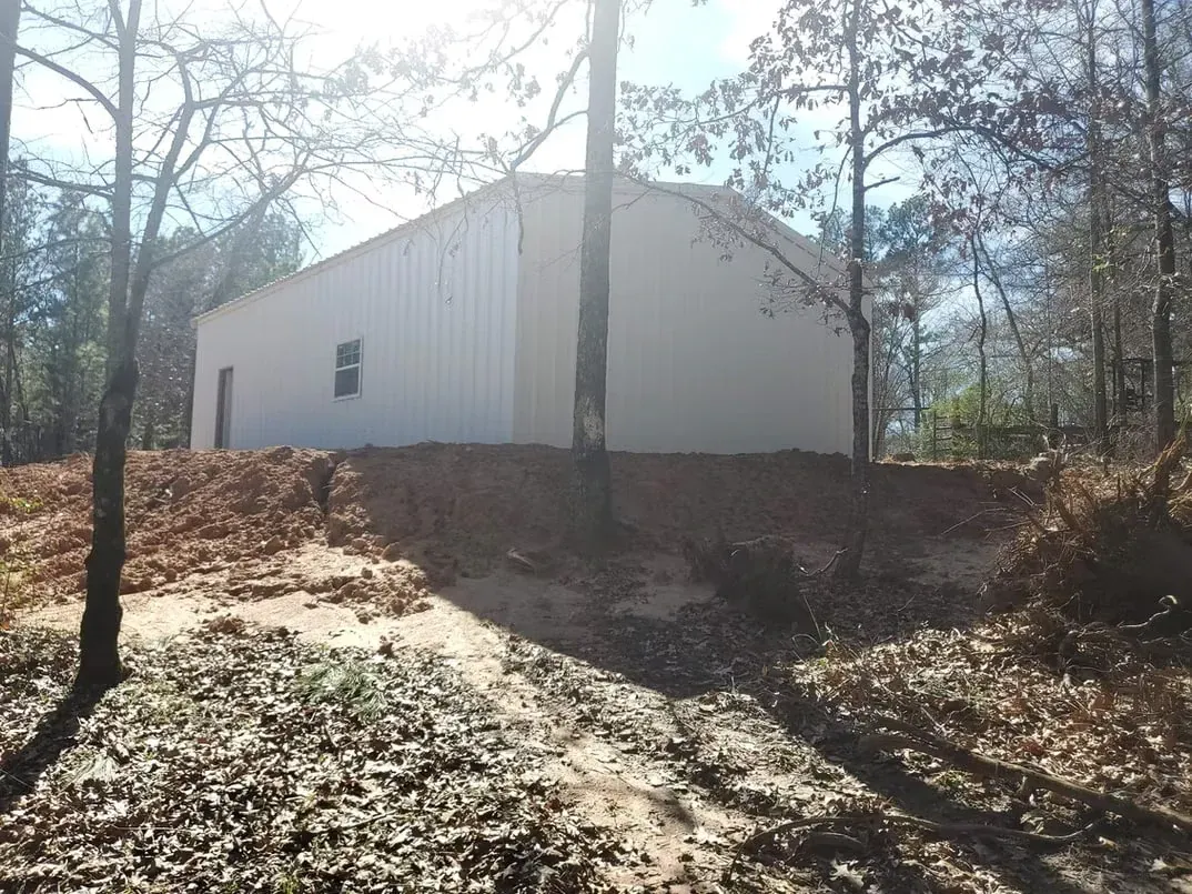 A white building is sitting on top of a hill in the middle of a forest.