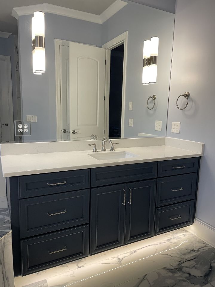 Modern bathroom vanity with dark cabinets, white countertop, dual sinks, and wall sconces