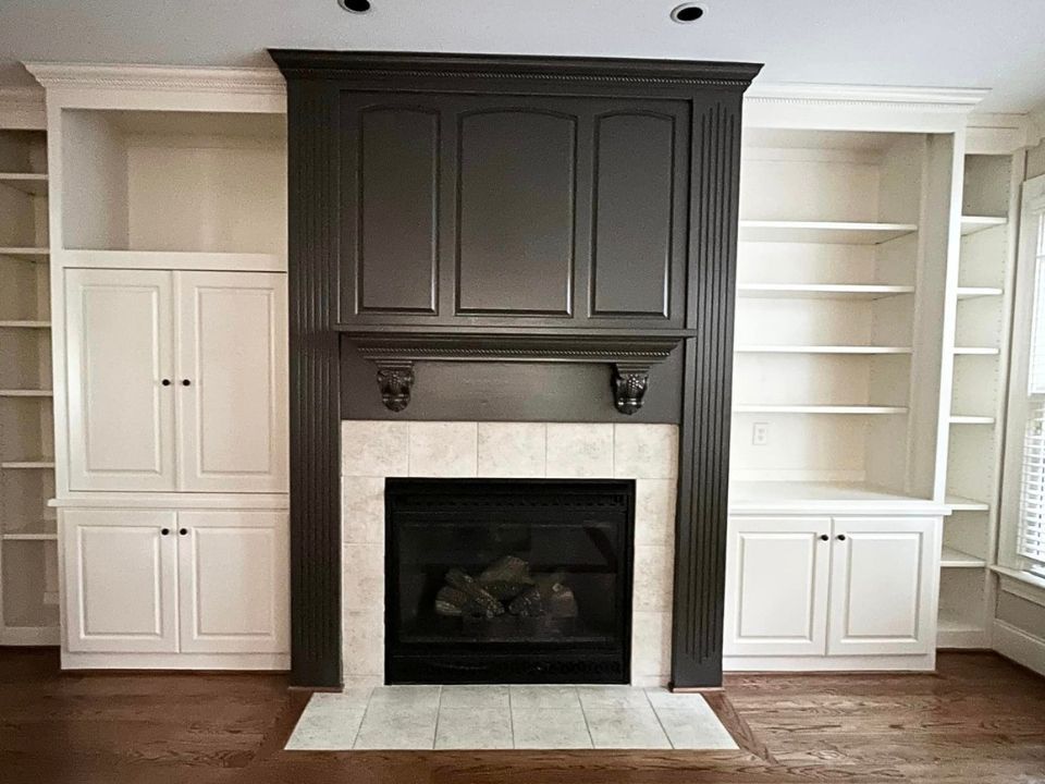 Built-in fireplace with dark mantel and white cabinets and shelves on both sides