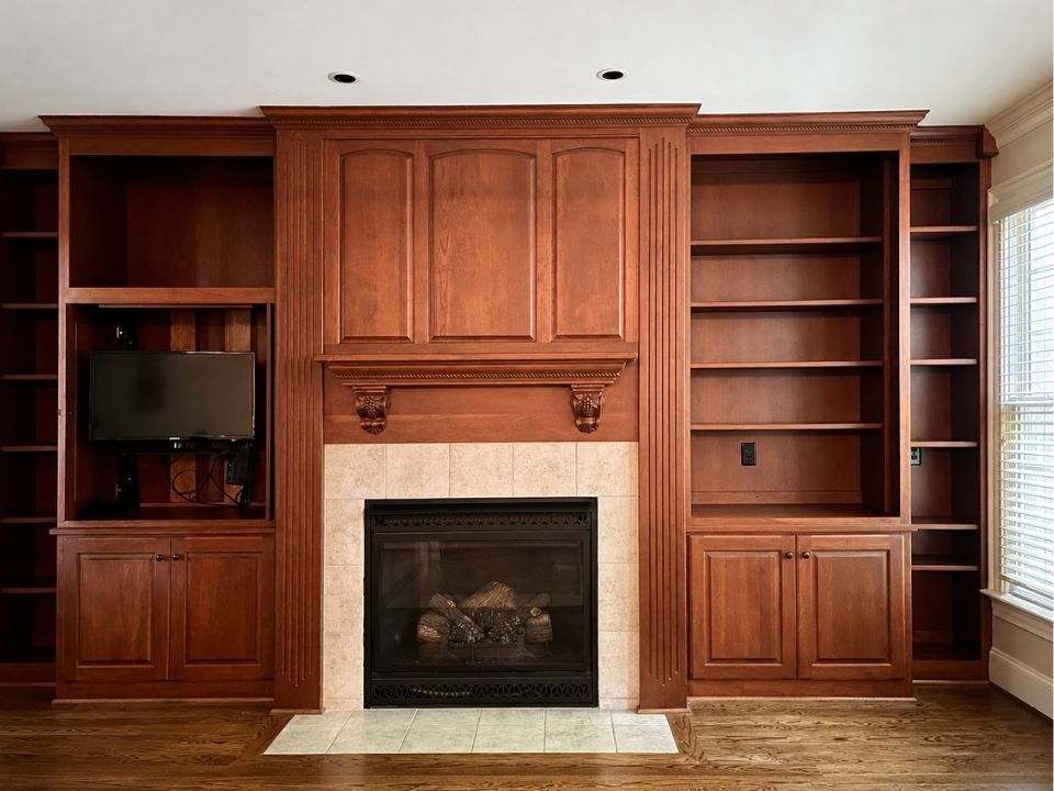 Built-in cherry wood entertainment center with fireplace and shelves in a living room