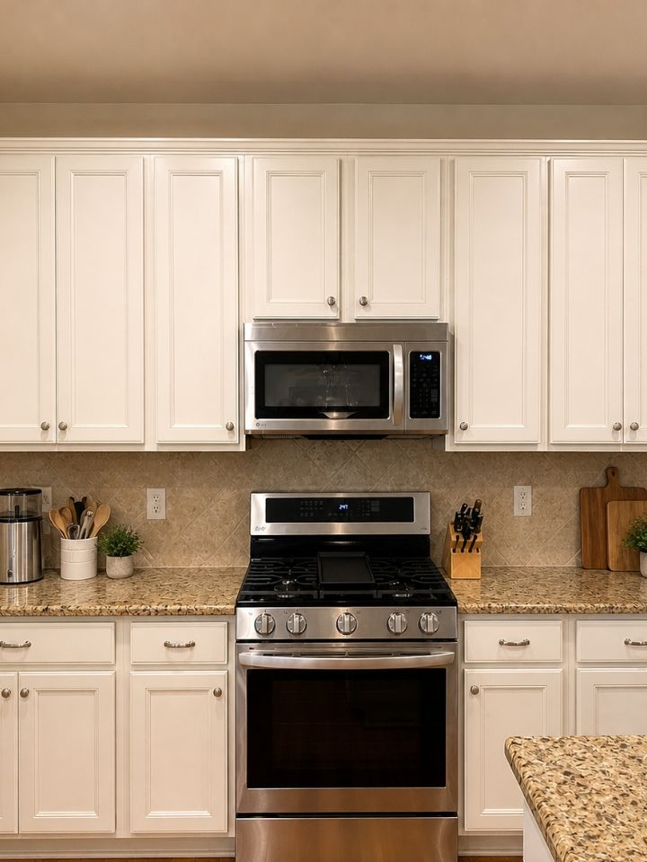 Modern kitchen with white cabinets, granite counters, and stainless steel stove and microwave.